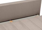 Detailansicht eines gepolsterten Bettes in Taupe/Beige mit hohem Kopfteil und gestepptem Polster, Blick schräg von oben auf Kopfteil und Liegefläche