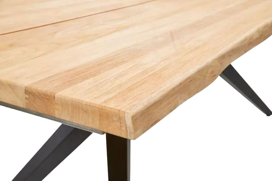 Nahaufnahme eines Esstisches mit heller Holzplatte und schwarzen Metallbeinen, Perspektive von der Seite