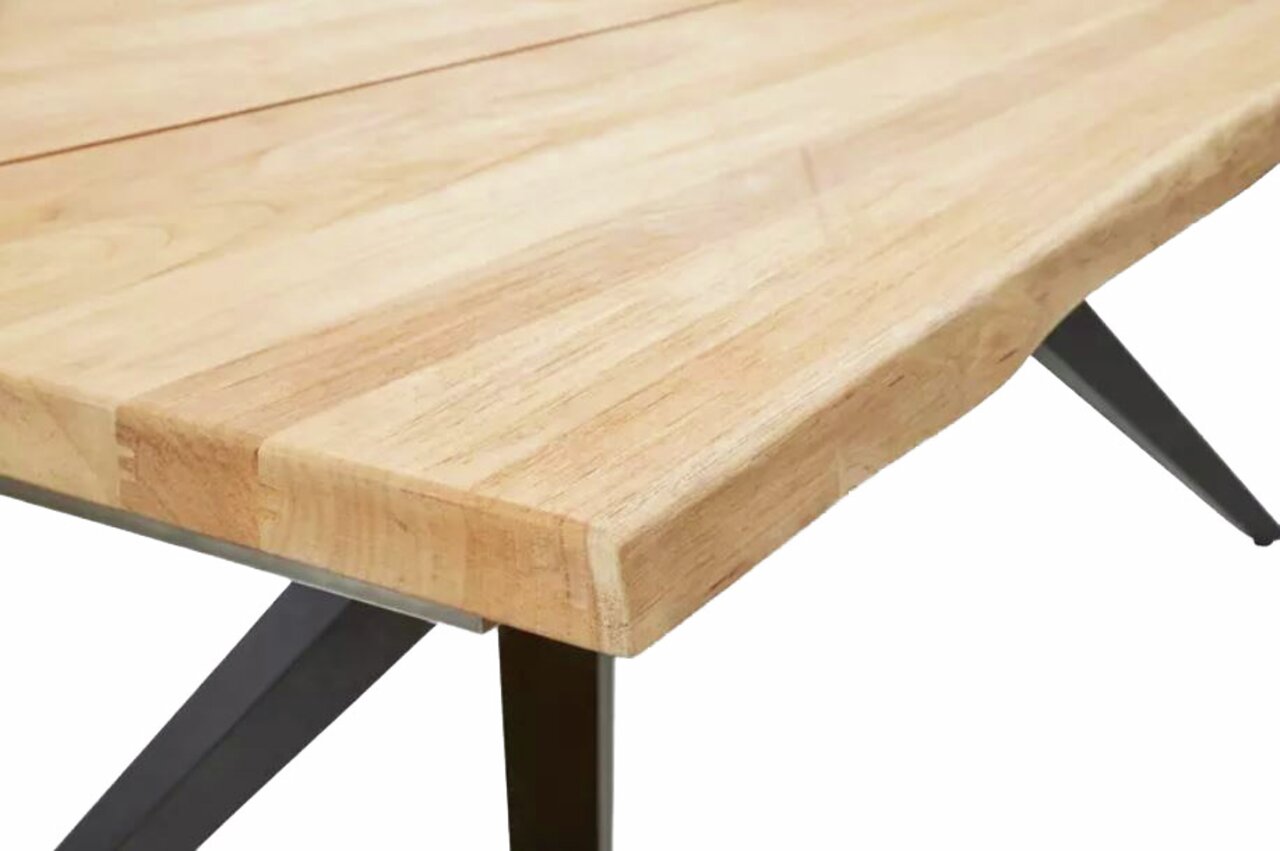 Nahaufnahme eines Esstisches mit heller Holzplatte und schwarzen Metallbeinen, Perspektive von der Seite