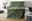 Grüne Jacquard-Decke mit schwarzem Buchstabenmuster, drapiert über einem grauen Sofa in einem modernen Wohnzimmer.