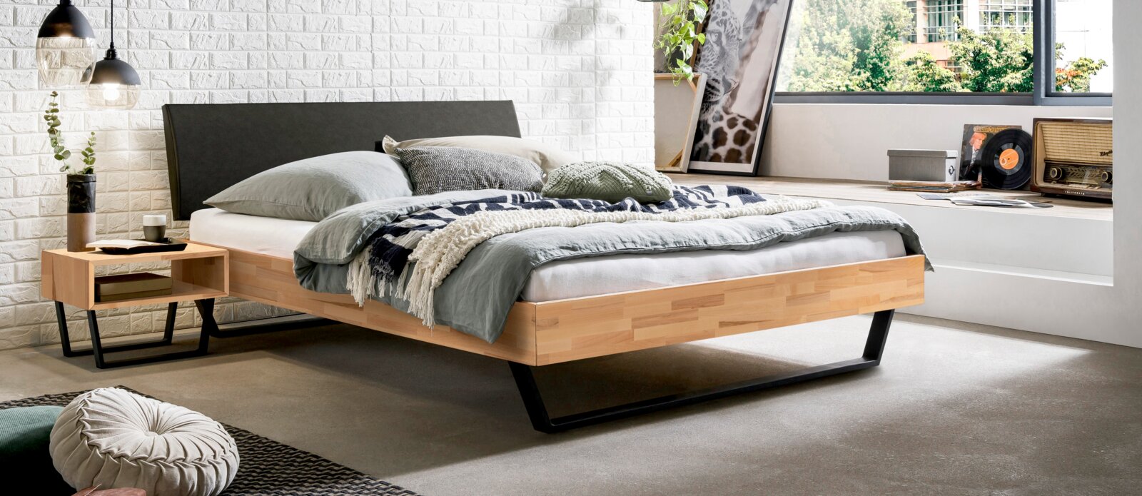 Modernes Schlafzimmer mit gepolstertem Kopfteil, Holzrahmen und stilvollem Nachttisch, seitliche Perspektive.
