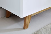 Nahaufnahme eines weißen Sideboards mit Holzbeinen, Perspektive von unten.
