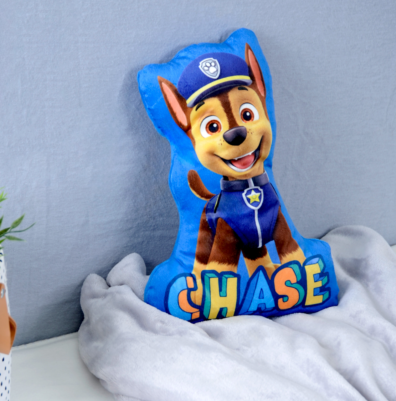 Chase-Formkissen mit einem fröhlichen Hundemotiv aus einer Kinderfernsehserie, frontal auf einem Bett platziert.