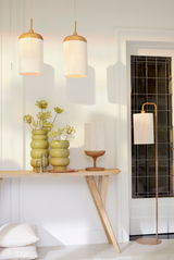 Zwei hängende Lampen mit Holzdetails und hellem Schirm, eine Tischlampe und eine Stehlampe in einem modernen Raum mit Holztisch und dekorativen Vasen, seitliche Perspektive.