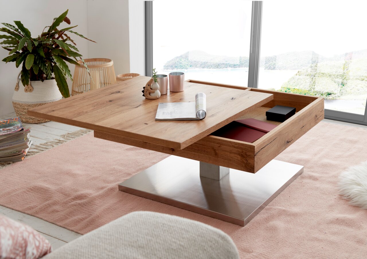 Moderne houten salontafel met lade, staande op een metalen voet, in een lichte woonkamer met uitzicht op een raam. Perspectief vanuit een schuine hoek van bovenaf.