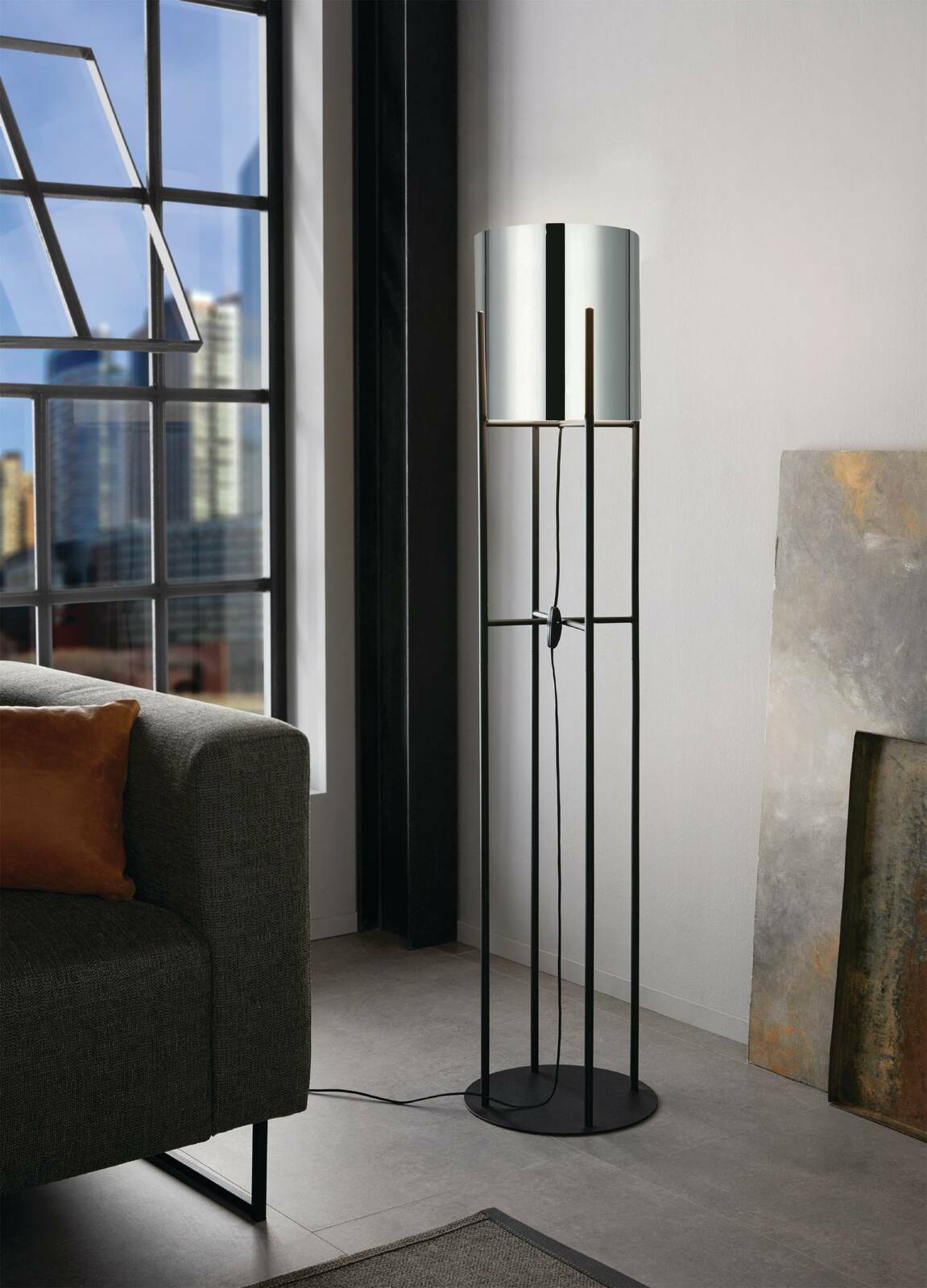 Moderne Stehleuchte GLASTONBURY in einem Wohnzimmer, seitliche Perspektive, mit schwarzem Metallgestell und zylindrischem Lampenschirm.