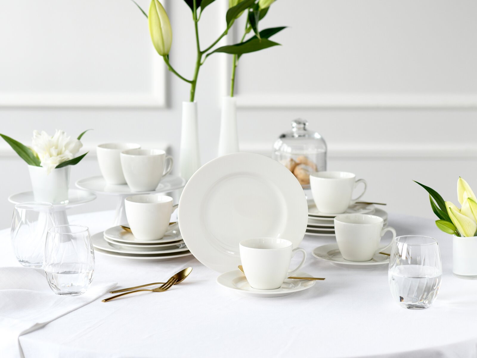 Creatable Kaffeeservice 18-tlg VENICE Modernes weißes Porzellan-Geschirrset mit Tassen, Untertassen und Tellern auf gedecktem Tisch, fotografiert aus leicht erhöhter Frontperspektive.