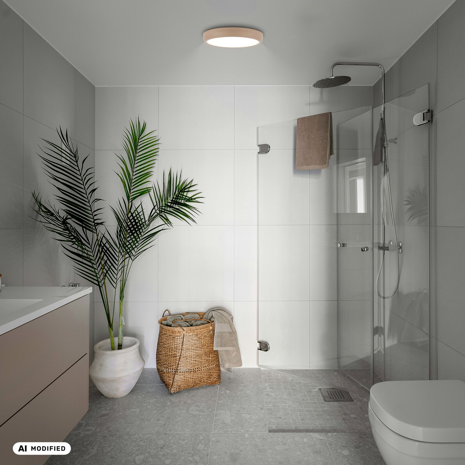 Moderne badkamer met ronde plafondlamp en glazen inloopdouche, gezien vanuit een frontale hoek met lichte bovenaanzichtperspectief; witte wandtegels, grijze vloer, groene kamerplant in pot en rieten wasmand.