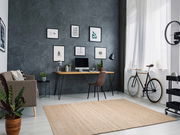Handgewebter Teppich in einem modernen Wohnzimmer mit grauer Wand, Schreibtisch, Stuhl und Fahrrad, aus der Vogelperspektive betrachtet.