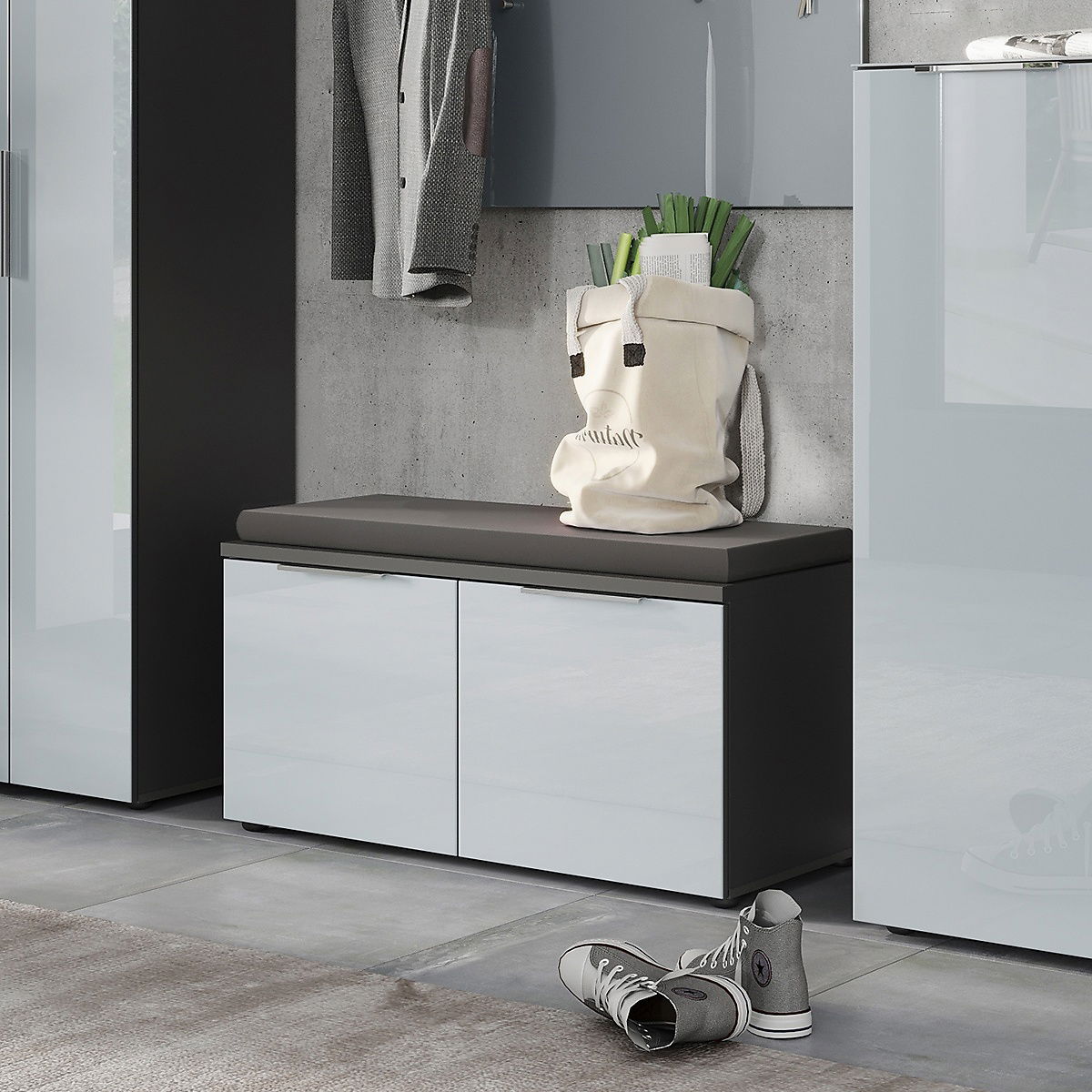 Moderne Garderobenbank mit grauem Sitzpolster, zwei Türen und glänzender Oberfläche, seitliche Perspektive.