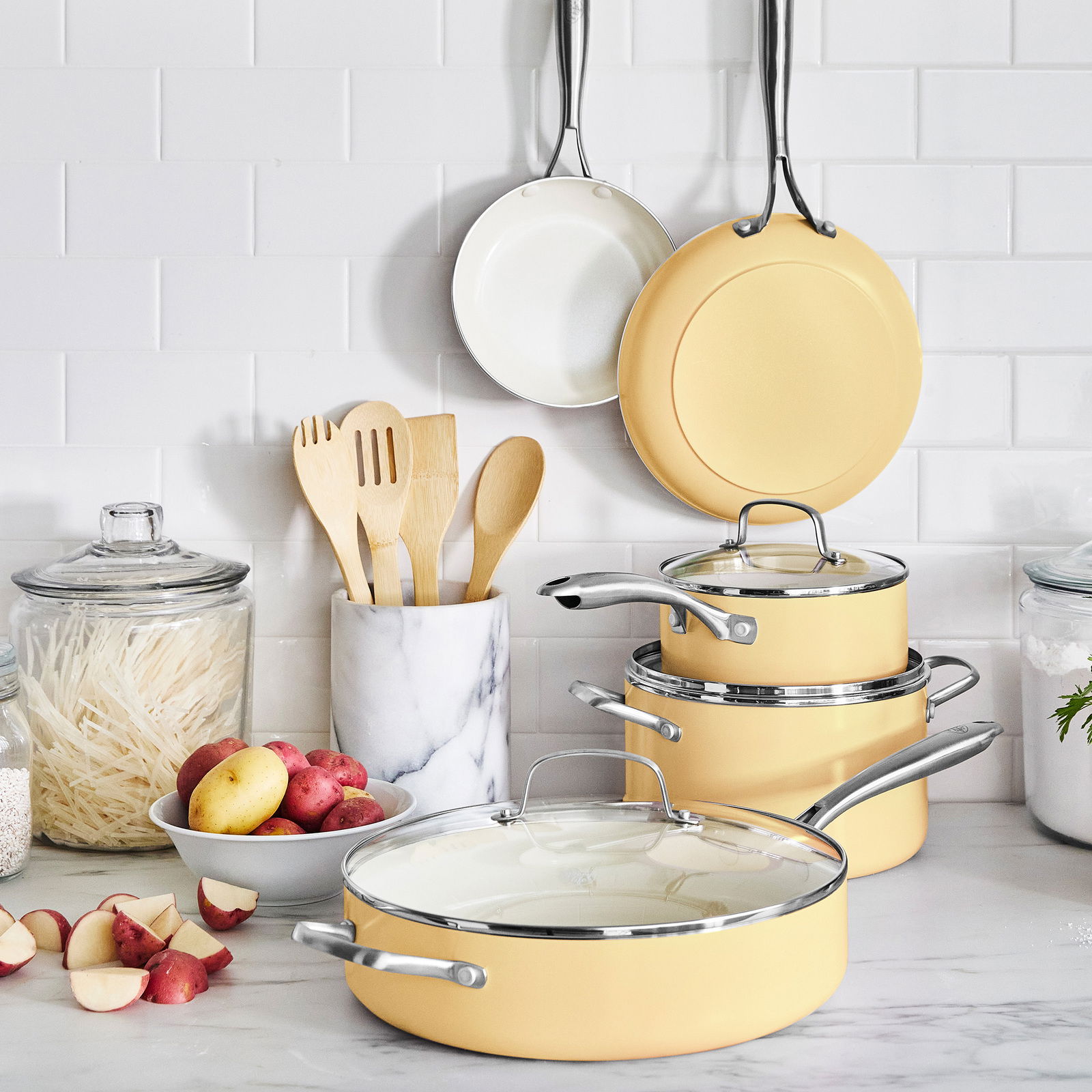 Kochgeschirr-Set Artizan 9-tlg in sanftem Gelb, bestehend aus Töpfen und Pfannen mit Glasdeckeln, präsentiert in einer modernen Küchenumgebung. Perspektive: Frontalansicht.