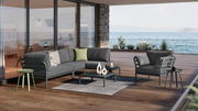 Moderner Beistelltisch auf einer Terrasse mit Meerblick, umgeben von stilvollen Gartenmöbeln.