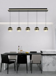 Moderne LED-Pendelleuchte mit fünf kugelförmigen Lampen, hängend über einem Esstisch in einem stilvollen Esszimmer, seitliche Perspektive.