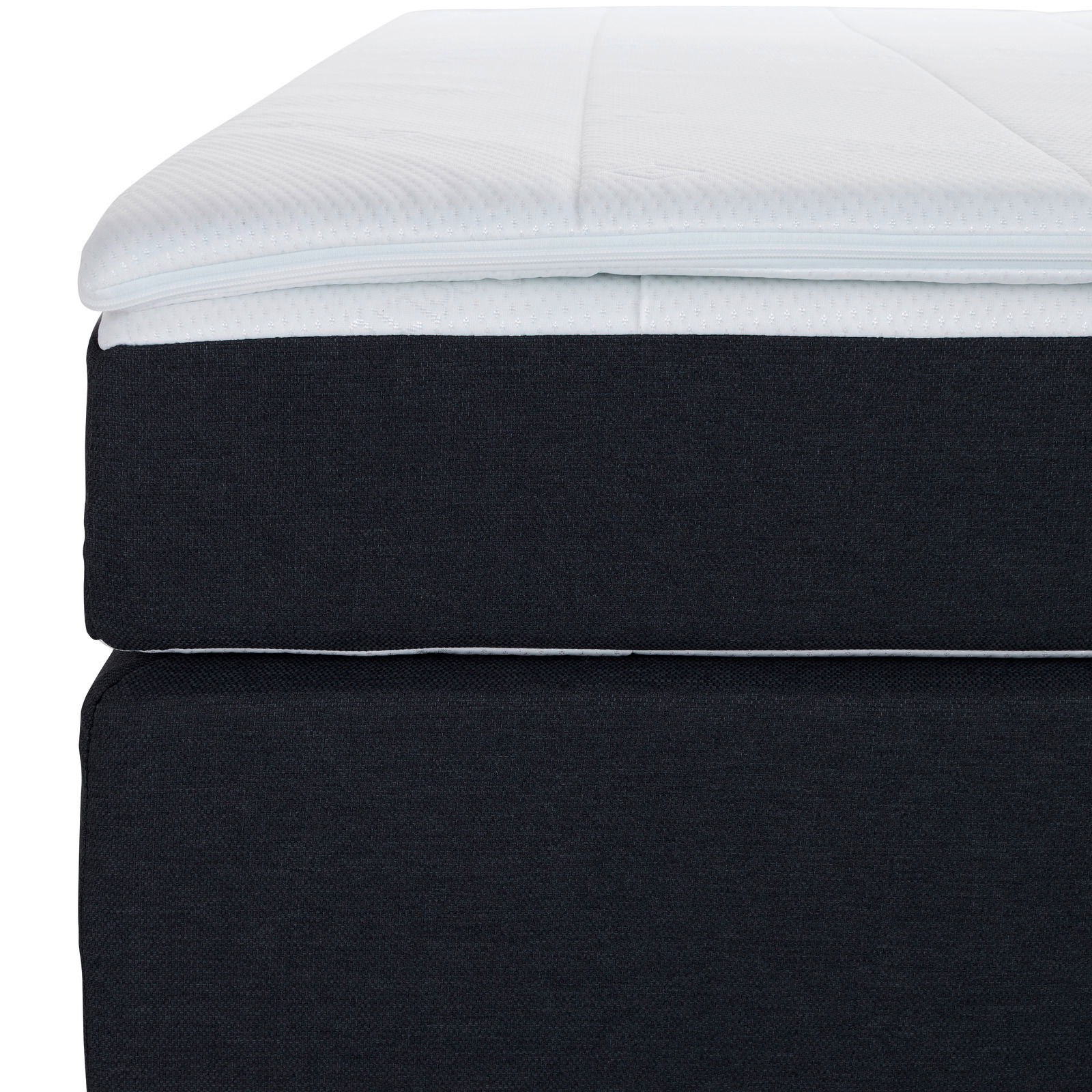Nahaufnahme eines Boxspringbetts mit dunklem Stoffbezug und weißem Topper, seitliche Perspektive