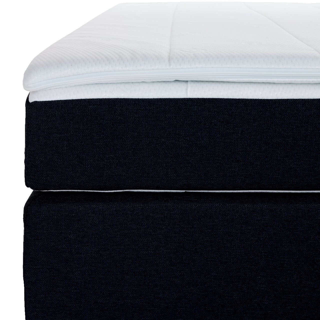 Nahaufnahme eines Boxspringbetts mit dunklem Stoffbezug und weißem Topper, seitliche Perspektive