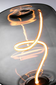 Nahaufnahme einer leuchtenden LED-Glühbirne mit geschwungenem Filament, seitliche Perspektive