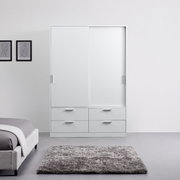 Moderne, witte kast met schuifdeuren, twee deuren en vier lades, gefotografeerd van voren in een minimalistisch ingerichte ruimte.