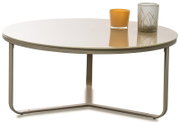 Runder Couchtisch mit transparenter Glasplatte und schlankem Metallgestell in Beige/Champagner, mit zwei Kerzenhaltern auf der Tischplatte; Frontansicht leicht von oben vor weißem Hintergrund.