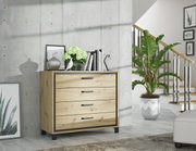Houten ladekast met vier lades, versierd met boeken, een vaas en een plant, in een moderne woonkamer met betonnen muur en trap, zijaanzicht