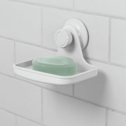 Weiße Seifenschale mit Gel-Lock-Technologie, an einer gefliesten Wand befestigt, mit einem Stück grüner Seife. Seitenansicht.