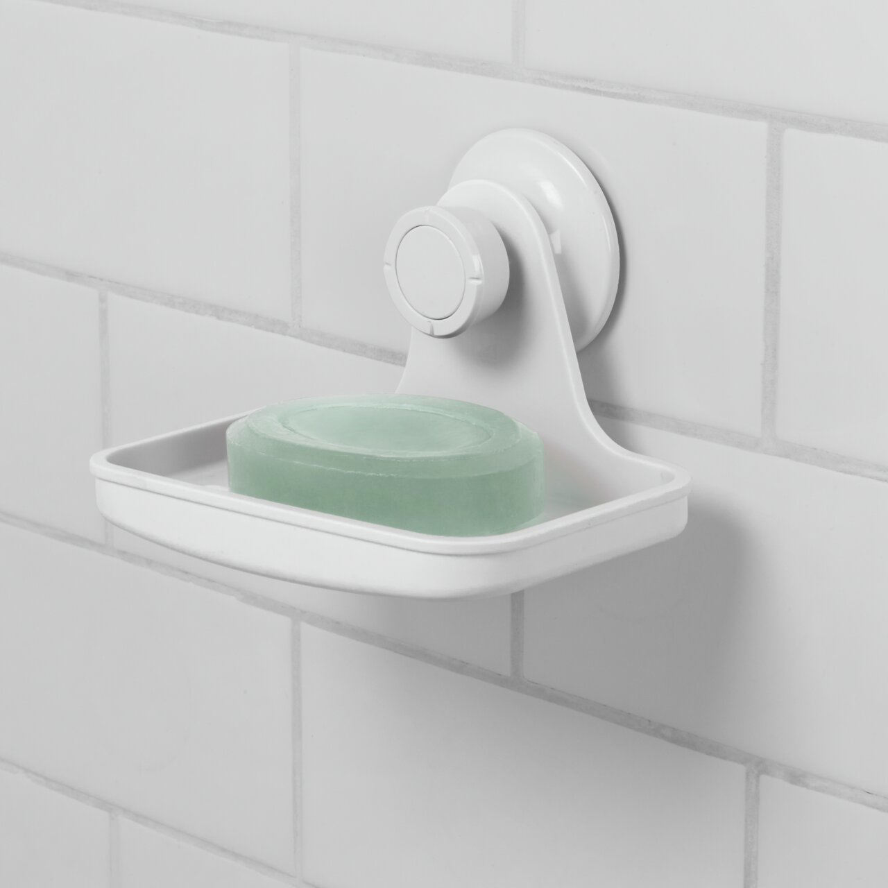 Weiße Seifenschale mit Gel-Lock-Technologie, an einer gefliesten Wand befestigt, mit einem Stück grüner Seife. Seitenansicht.