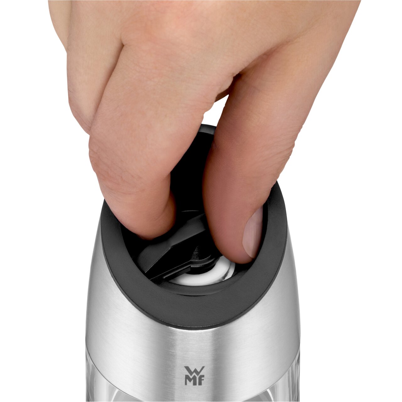 Nahaufnahme einer Hand, die den Deckel einer elektrischen Mühle aus Edelstahl öffnet.