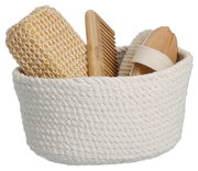 Aufbewahrungskorb aus geflochtenem Material, gefüllt mit einem Kamm, einer Bürste und einem Schwamm, seitliche Perspektive