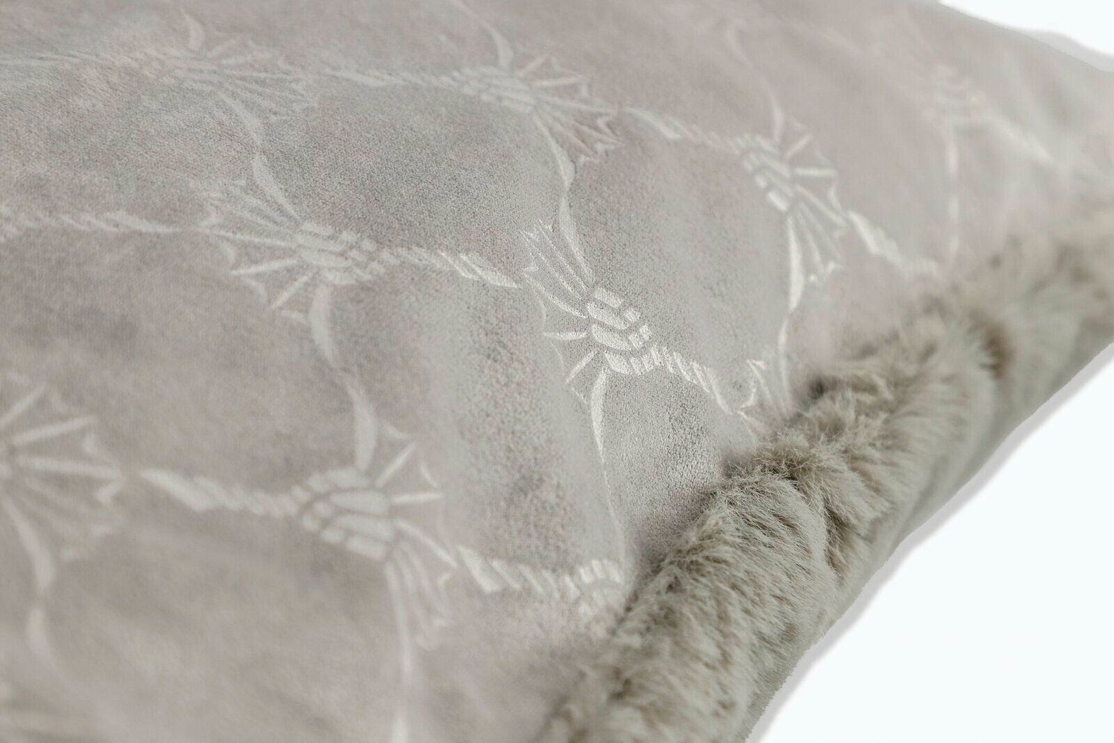 Nahaufnahme eines weichen, grauen Kissens mit dekorativem Muster und flauschigem Rand, seitliche Perspektive.