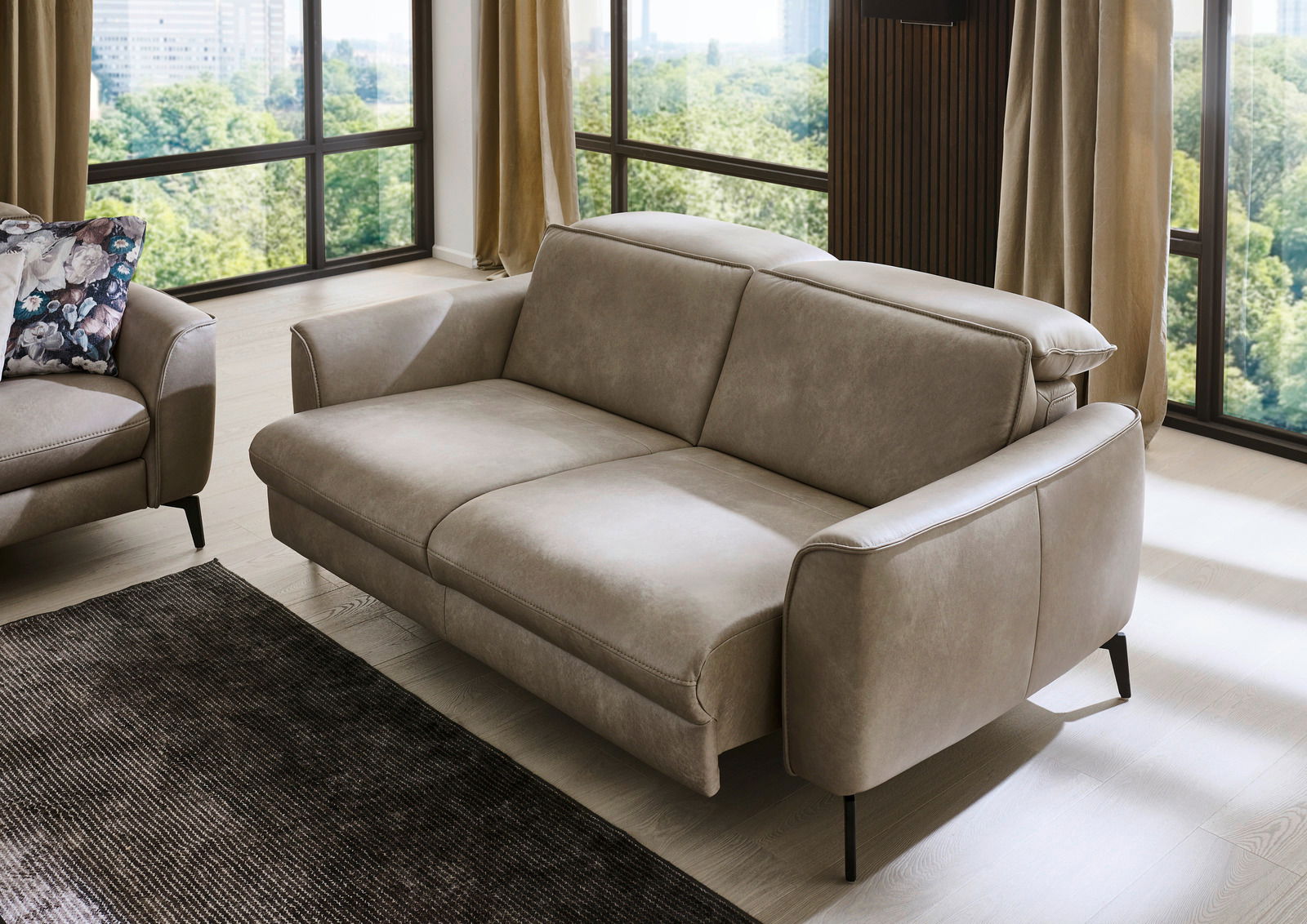 Modernes beiges Sofa in einem hellen Wohnzimmer mit großen Fenstern, seitliche Perspektive.