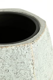 Nahaufnahme eines Topfes mit rauer, steinartiger Oberfläche und schwarzem Innenrand, von oben betrachtet.