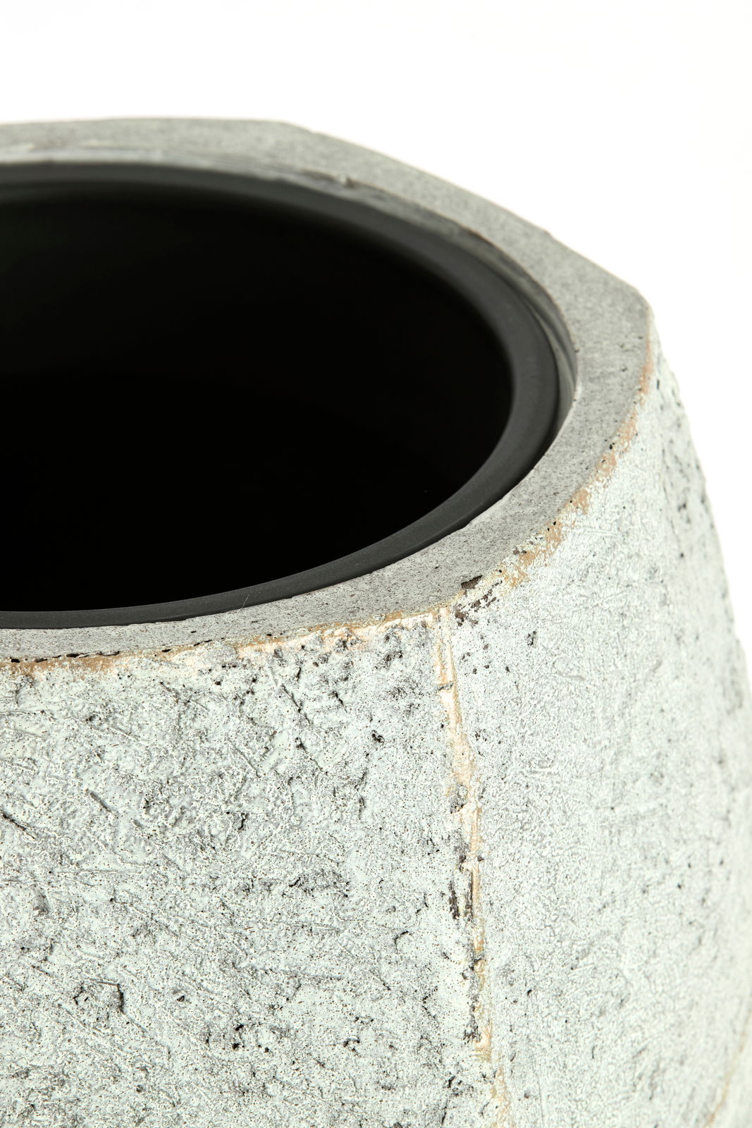 Nahaufnahme eines Topfes mit rauer, steinartiger Oberfläche und schwarzem Innenrand, von oben betrachtet.