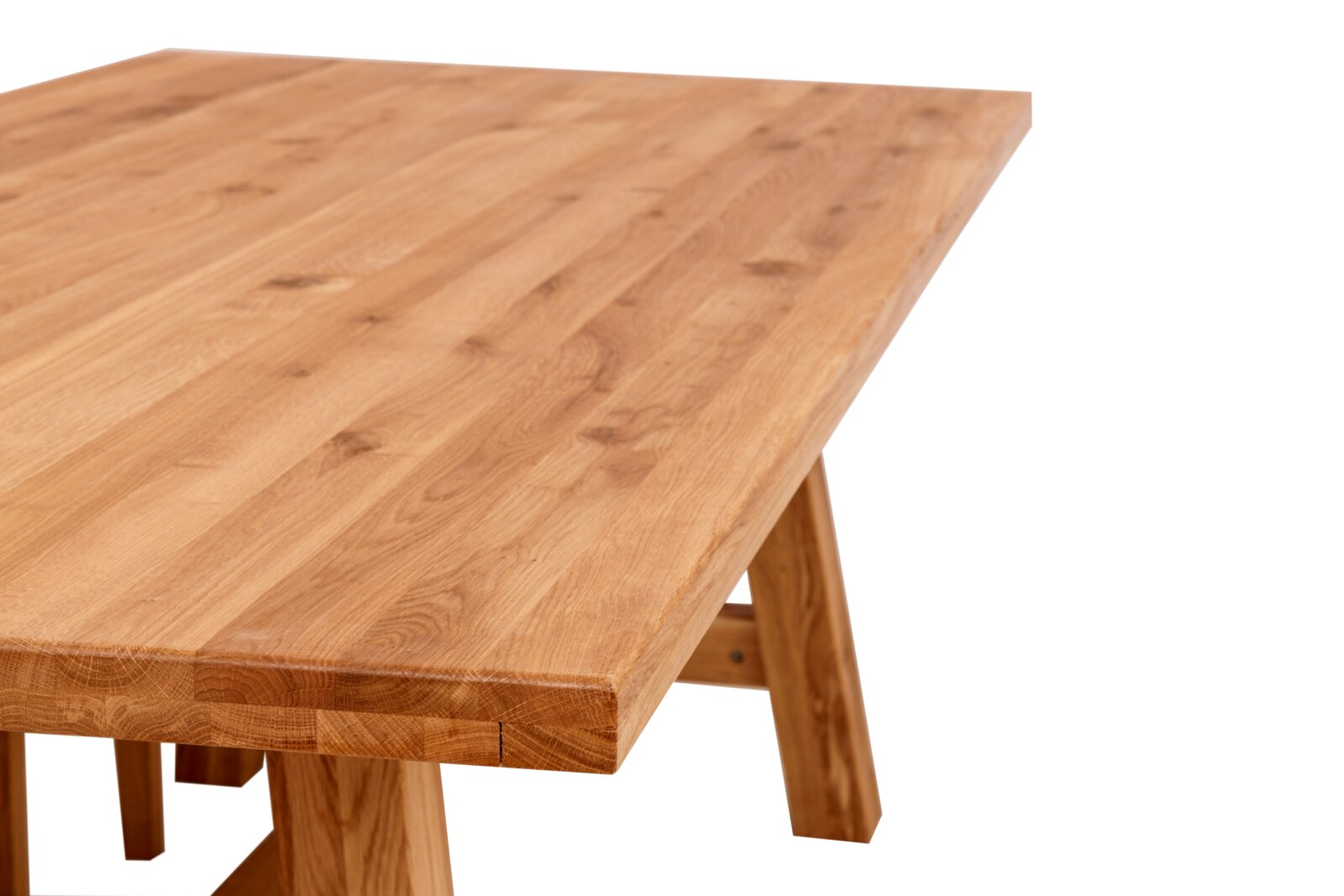 Massiver Holztisch mit naturfarbener, geölter Tischplatte und sichtbarer Maserung, Detailansicht aus schräger Perspektive von oben auf die Tischkante