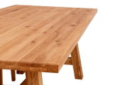 Massiver Holztisch mit naturfarbener, geölter Tischplatte und sichtbarer Maserung, Detailansicht aus schräger Perspektive von oben auf die Tischkante