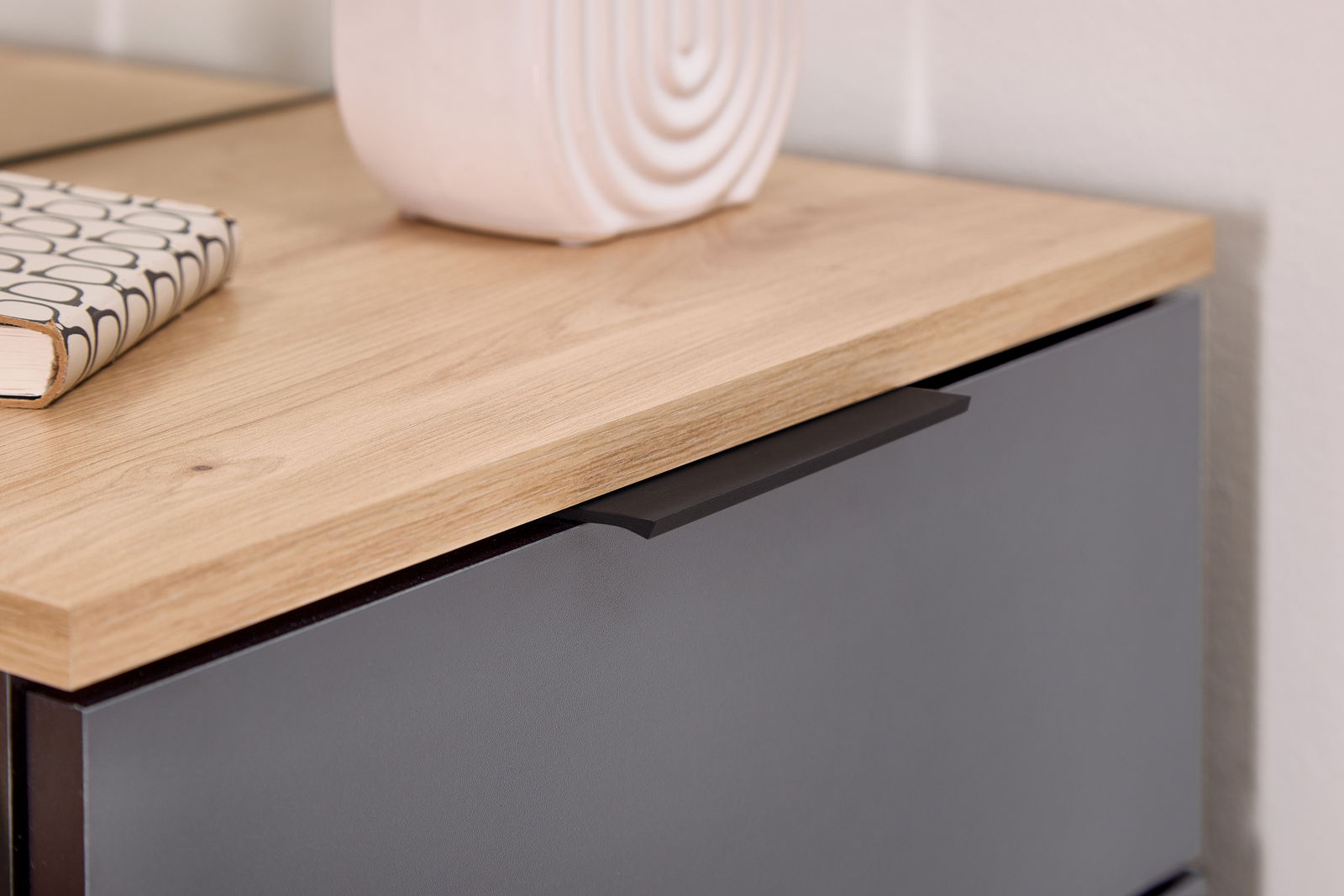 Nahaufnahme einer Kompaktgarderobe mit Holzoberfläche und dunkler Schublade, seitliche Perspektive