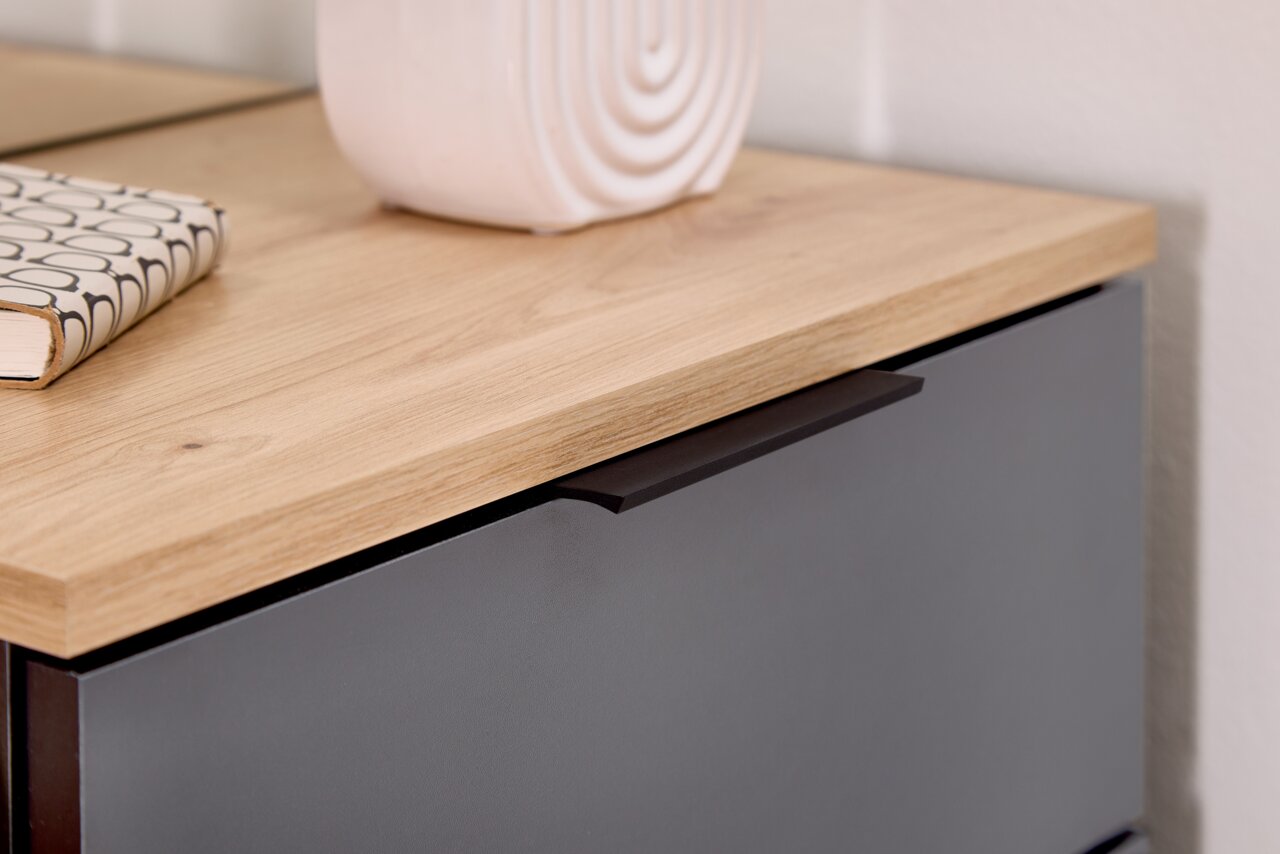 Nahaufnahme einer Kompaktgarderobe mit Holzoberfläche und dunkler Schublade, seitliche Perspektive