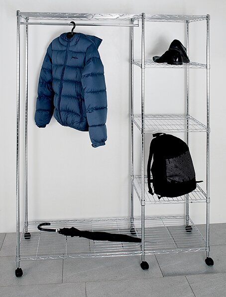 Silbernes, rollbares Kleiderregal aus Metall mit Seitenregal; blaue Steppjacke hängt am Bügel, oben schwarze Schuhe, unten schwarzer Rucksack und ein Schirm auf der unteren Ablage, Frontalansicht.