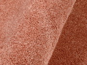 Nahaufnahme eines rosafarbenen Uni-Teppichs mit weicher Textur, perspektivisch von der Seite aufgenommen.