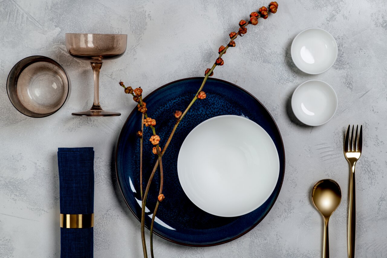 Elegantes Sekt- und Dessertschalen-Set in einer stilvollen Tischdekoration von oben betrachtet, mit goldfarbenem Besteck und blauen Akzenten.