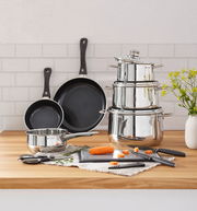 Kochtopf-Starter-Set 10-tlg. aus Edelstahl mit Töpfen, Pfannen und Küchenutensilien auf einer Holzarbeitsplatte, seitliche Perspektive.