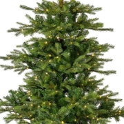 Vooraanzicht van een volle groene kunstkerstboom met realistische takken en warmwitte ledverlichting tegen een witte achtergrond