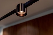 Zwarte cilindervormige LED-spot op een rail, warm wit licht, gefotografeerd van onderaf in een moderne interieursetting