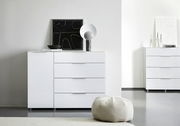 Weiße Kombikommode mit vier Schubladen und einer Tür, dekoriert mit einem modernen Kunstwerk und einer Lampe, aus der Frontalperspektive fotografiert.