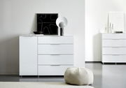 Weiße Kombikommode mit vier Schubladen und einer Tür, dekoriert mit einem modernen Kunstwerk und einer Lampe, aus der Frontalperspektive fotografiert.