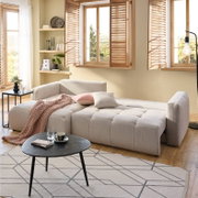 Ecksofa London in einem modernen Wohnzimmer, beige gepolstert, mit Kissen und Decke, aus der Perspektive von vorne links.