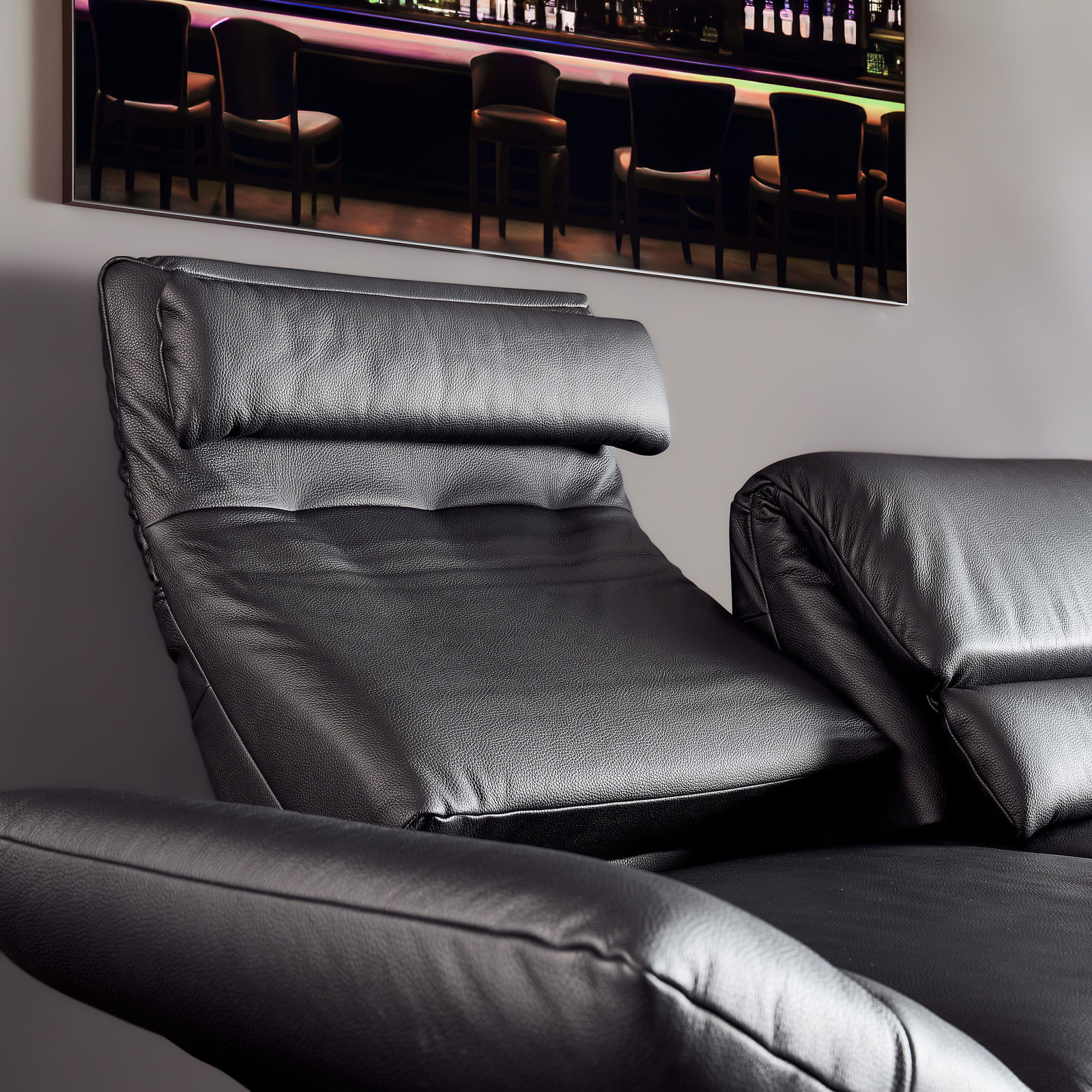 Nahaufnahme eines schwarzen Ledersofas mit verstellbarer Rückenlehne und Armlehnen, seitliche Perspektive.