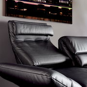 Nahaufnahme eines schwarzen Ledersofas mit verstellbarer Rückenlehne und Armlehnen, seitliche Perspektive.