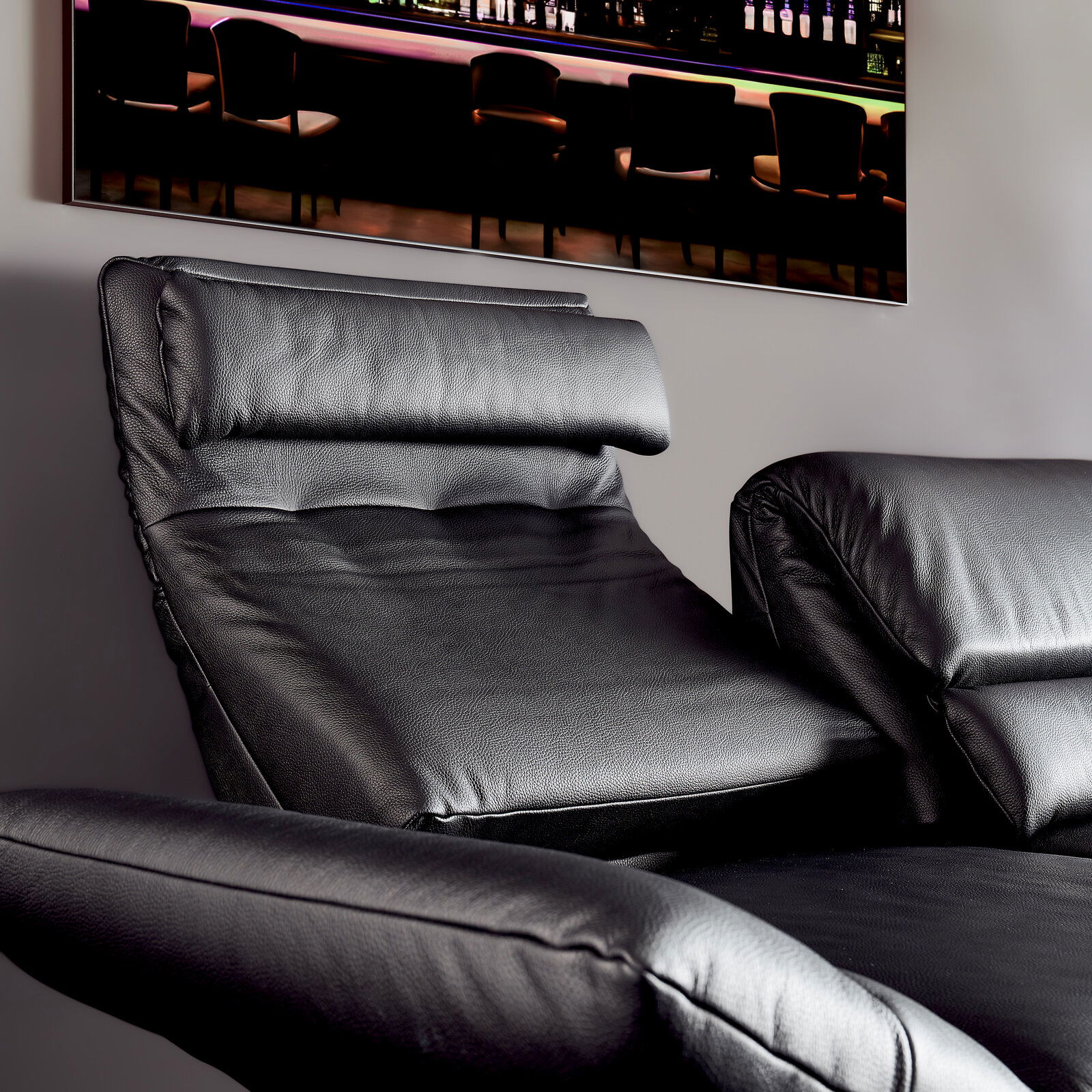 Nahaufnahme eines schwarzen Ledersofas mit verstellbarer Rückenlehne und Armlehnen, seitliche Perspektive.