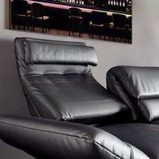 Nahaufnahme eines schwarzen Ledersofas mit verstellbarer Rückenlehne und Armlehnen, seitliche Perspektive.