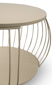 Close-up schuin zijaanzicht van een ronde beige metalen bijzettafel met draadframe en onderblad op witte achtergrond
