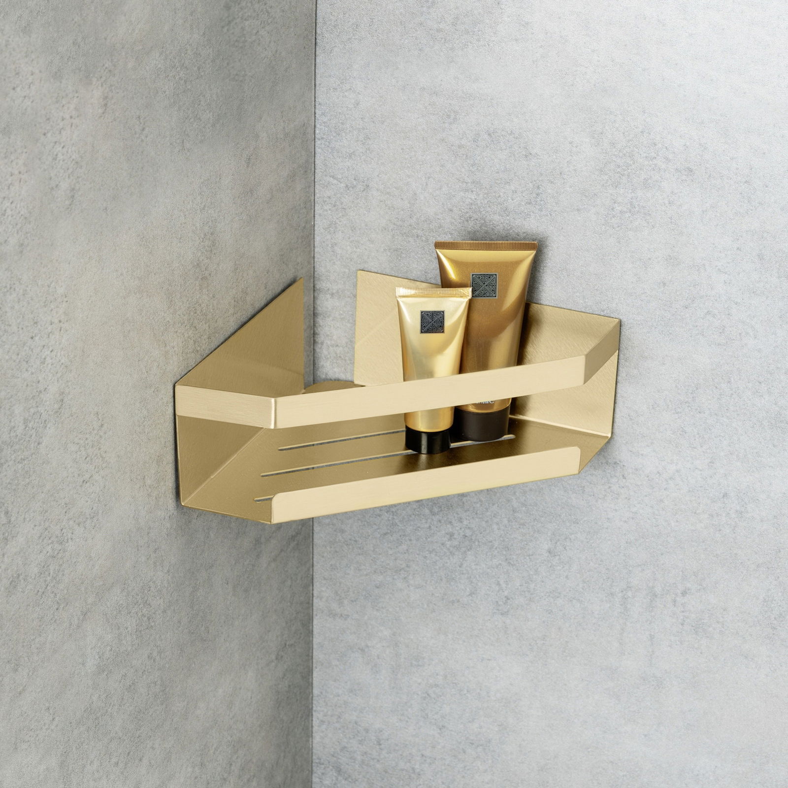 Goldene Eckablage Meleto mit zwei Tuben, an einer grauen Wand montiert, seitliche Perspektive.